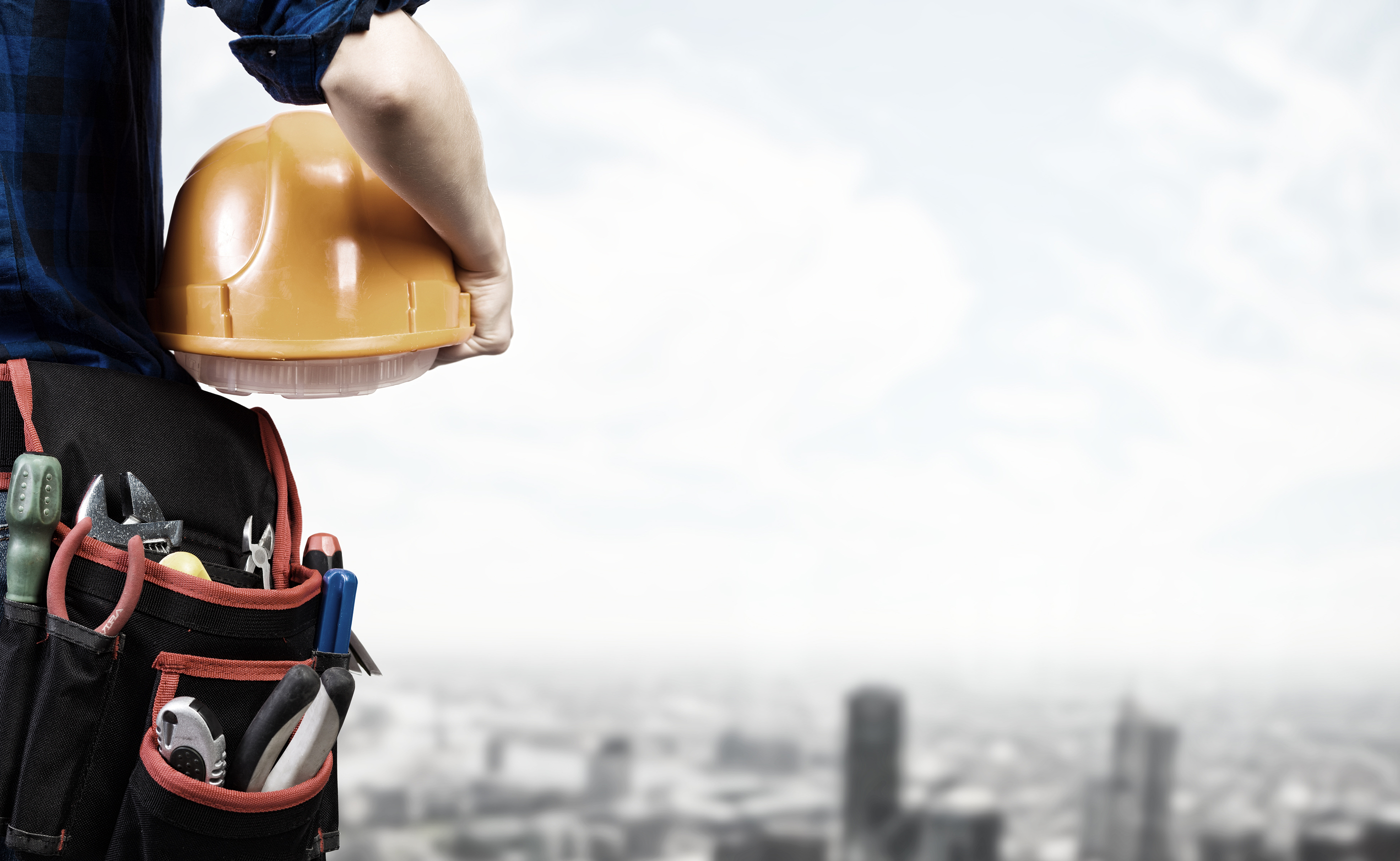 Close up of woman mechanic with yellow helmet in hand against city background