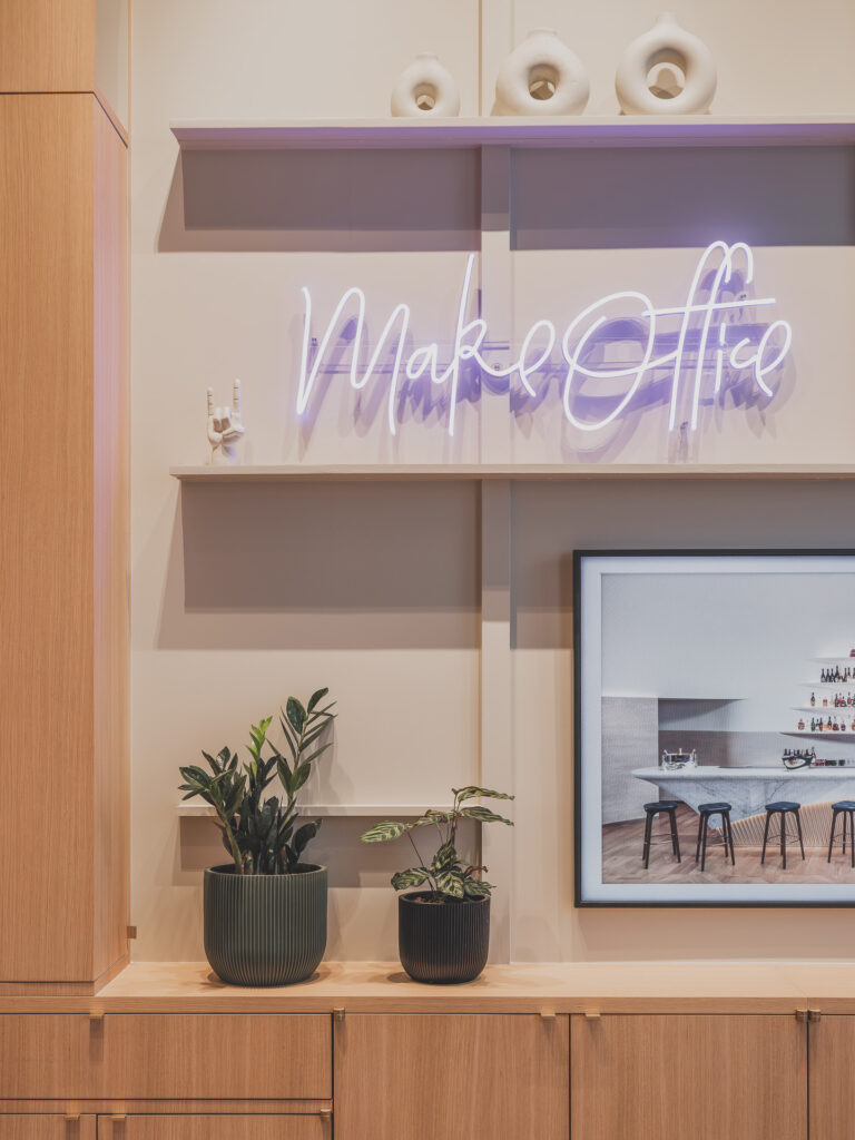 nouveaux bureaux MAKE Office avec néon au nom de l'entreprise, des plantes sur le plan de travail et un cadre avec aménagement de bureau. Photo d'Alexis Paoli©